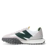 Championes urbanos New Balance modelo XC-72, con diseño combinado en blanco, gris y verde. Presentan una silueta retro-futurista con superposiciones de gamuza, paneles de cuero y una suela de goma dentada distintiva que se extiende hacia la puntera.