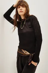 Polera negra de manga larga con diseño combinado, presentando un cuerpo de tejido liso y mangas de encaje con textura. Posee cuello alto y un ajuste entallado al cuerpo.