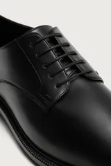 Zapato de vestir tipo derby, color marrón oscuro, con parte superior lisa, horma redonda, cordones y suela con ligero tacón.