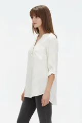 Blusa de viscosa color bordó, con cuello en V, cierre frontal parcial con botones, mangas tres cuartos y bolsillo aplicado en el pecho.