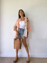 Bolso matero de cuero color beige con textura tipo piel de cocodrilo, detalles en cuero color marrón y borlas decorativas.