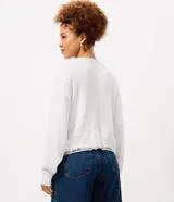 Cardigan de punto liviano color blanco, con cierre frontal de botones, mangas largas con hombros caídos y detalle de encaje en el ruedo.