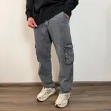 Jean cargo de corte recto en color gris con efecto lavado. Presenta bolsillos laterales tipo cargo con solapa y cierre de botón y bragueta.