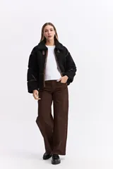 Campera tipo teddy de textura suave y acabado de peluche en color beige. Presenta cuello amplio con detalle de hebilla, cierre frontal y recortes en contraste de color marrón que marcan la estructura de la prenda.