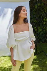 Blusa blanca strapless con mangas largas abullonadas.