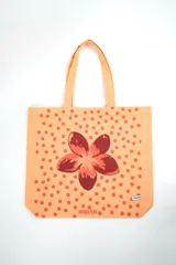 Bolso tipo tote bag de color crudo con estampado de flores celestes y centros azul oscuro. Cuenta con doble asa de hombro en tono crudo y etiqueta con la marca en el frente.