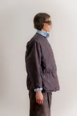 Campera reversible de estilo parka, color celeste, con diseño capitoneado con patrón de flores. Presenta ajuste elástico en la cintura, cuello alto y mangas largas. Incluye parche de marca en la parte superior de la espalda.