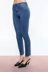 Pantalón de jean azul elastizado, de corte skinny, tiro alto y terminación desflecada en el ruedo.