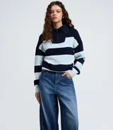 Pantalón de jean azul con corte barrel, cintura alta y estructura amplia. Presenta diseño de cinco bolsillos, cierre frontal con botón y trabillas para cinturón.