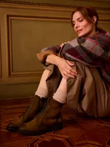 Borcego acordonado de cuero verde oliva, con cordones negros, cierre lateral para facilitar el calce y suela de goma.
