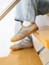 Zapatillas urbanas de diseño retro en tonos beige, marrón y celeste, confeccionadas en serraje con suela de goma color caramelo y cordones blancos.