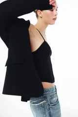 Corsé de escote en pico con tirantes finos, confeccionado en una combinación de tejido opaco y paneles de tul transparente, con costuras visibles a tono.