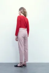 Pantalón rosa pastel con cintura elastizada, bolsillos laterales y cinto con hebilla metálica.