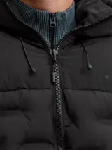 Campera puffer negra con capucha ajustable, cierre frontal y bolsillos laterales. Presenta un diseño acolchado con textura geométrica en el frente, puños con ajuste de velcro y logo sutil en el pecho.