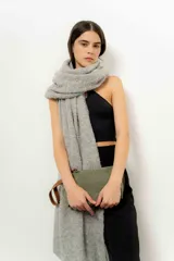 Sobre de mano color verde oliva, confeccionado en cuero gamuzado, con cierre superior y tira de cuero marrón en el lateral.