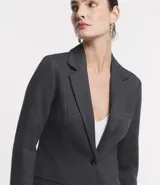 Blazer alargado color gris oscuro, con cuello solapa, bolsillos incorporados y cierre frontal con dos botones.