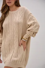 Sweater largo de punto con diseño de trenzas y rombos en el frente y mangas. Posee cuello redondo, mangas largas con puños ajustados y un calce holgado.