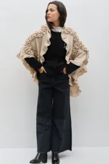 Chal de lana color marrón con diseño envolvente, decorado con volados aplicados en toda la superficie que aportan textura y movimiento.