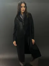 Tapado largo de paño de lana color negro con estampado abstracto brillante en el frente. Tiene cuello con solapas, bolsillos laterales y terminación al tallo vivo.