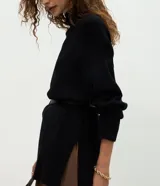 Suéter de punto de corte oversize y largo alargado, con cuello alto, mangas largas y aberturas laterales sutiles. Presenta puños y ruedo con acabado acanalado.
