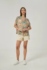 Blusa de lino con diseño estampado multicolor en tonos tostado, turquesa y rosado, corte holgado, mangas cortas y escote en V.