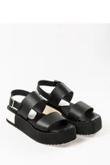 Sandalias negras de cuero con plataforma blanca y hebilla metálica.