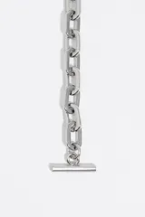 Collar de cadena plateada con dos dijes centrales en forma de panteras doradas enfrentadas. Las panteras presentan detalles de manchas en esmalte negro e incrustaciones de vidrio. Cuenta con un cierre de barra tipo T ajustable.