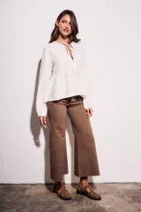 Blusa color crudo de viscosa y lino con bordados en el frente, escote con lazo y mangas largas. Corte holgado con frunce en la cintura.