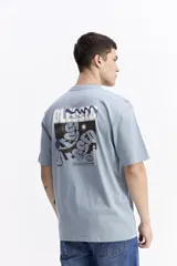 Remera de manga corta color celeste claro, con cuello redondo y estampado gráfico grande en la espalda con la palabra "BLESSED" y frases como "BE GRATEFUL EVERY MOMENT". Incluye el logo de la marca Mistral.