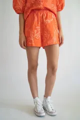 Short de lino y algodón color naranja con estampado de hojas y flores en tonos claros, con cintura elástica.