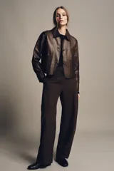 Pantalón de tiro medio color marrón oscuro con textura acanalada o plisada verticalmente. Presenta pierna ancha y cintura con trabillas.