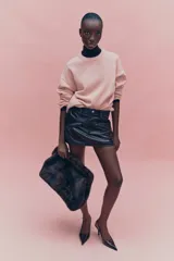 Buzo oversized rosado de punto suave, con cuello redondo y ribetes acanalados en cuello, puños y bajo. Hombros marcadamente caídos.