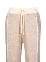 Pantalon de punto color beige con textura jaspeada, corte recto y holgado. Presenta cintura elastizada con cordón de ajuste y detalles de costuras verticales en color crema a lo largo de las piernas.