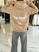 Canguro negro oversize con capucha y gran estampado blanco en la espalda con el texto "Top Style", "Dream big. Work hard. Make it real.", "SINCE 2021" y un código de barras.