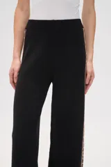 Pantalon de tejido de punto color crema, de corte ancho y tiro alto. Presenta una franja lateral con estampado animal print a lo largo de ambas piernas.