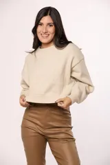 Buzo tejido de punto color beige, con cuello redondo, mangas largas con puños ajustados y corte holgado.