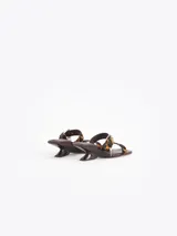Sandalia de taco bajo con estampa animal print de leopardo, tiras finas de cuero, hebilla metálica y dijes colgantes.