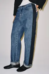 Jeans wide leg de tiro medio y corte recto de Zara, con efecto lavado y detalle de paneles de denim oscuro a contratono en los laterales. Cuenta con bolsillos clásicos y botamangas con vuelta.
