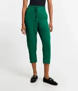 Pantalón de crepé rojo, modelo estilo pijama, de corte fluido, con cintura elástica y lazo de ajuste con terminales metálicas. Cuenta con bolsillos laterales y cierre frontal con cremallera y botón.