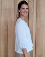 Remera blanca con cuello en V, cuerpo de algodón y mangas abullonadas de encaje bordado con puños elásticos.