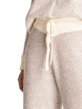 Pantalon de punto color beige con textura jaspeada, corte recto y holgado. Presenta cintura elastizada con cordón de ajuste y detalles de costuras verticales en color crema a lo largo de las piernas.