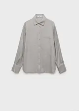 Camisa de viscosa color gris claro, de corte recto, con cuello camisero, cierre frontal con botones, bolsillo de parche en el pecho y mangas largas abotonadas.