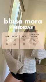 Blusa plateada de tejido metalizado con escote bote que puede usarse recto o caído en un hombro.