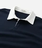 Buzo de manga larga color azul marino, confeccionado en tejido de algodón con felpa, con cuello polo blanco contrastante y abertura frontal con botones.