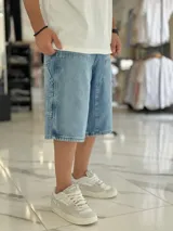 Bermuda de jean estilo carpintero, color celeste, con bolsillos laterales amplios, presilla para herramientas y diseño amplio de corte oversize.