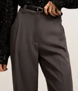 Pantalón de sastrería corte wide leg, color gris oscuro, con cintura alta, pliegues frontales, bolsillos laterales y trabillas para cinturón. Incluye un cinturón fino de material sintético con hebilla metálica.