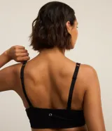 Top deportivo negro, confeccionado en tejido seamless de poliamida y elastano, con escote en U y breteles ajustables. Presenta una banda inferior texturizada y copas removibles.
