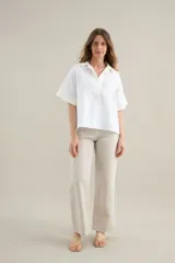 Blusa blanca de lino con silueta cómoda y relajada, escote en V con cuello polo y detalles en algodón.