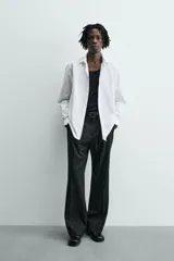 Camisa blanca de corte slim fit, confeccionada en tejido de algodón. Presenta cuello italiano, manga larga con puño abotonado y cierre frontal de botonadura.