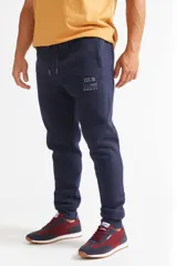 Pantalón de jogging azul marino con corte ajustado, puños elásticos en los tobillos, cintura con cordón ajustable y bolsillos laterales. Presenta un pequeño logo estampado en el muslo.